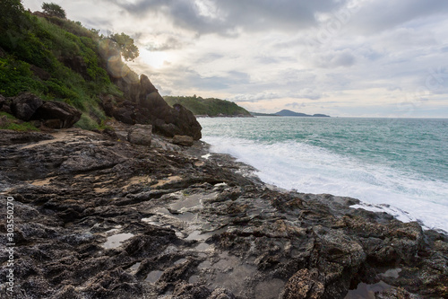 Rocky cape in Phuket, Andaman Sea, landscape in cloudy weather, rocks and bushes on the shore