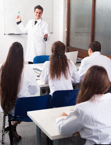 Students in white coats listen to lecture in audience