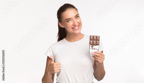 Girl Holding Chocolate Gesturing Thumbs Up Standing, Studio Shot