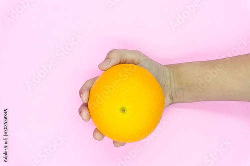 Organic freshness Orange cutting on kid hand Isolated pink background