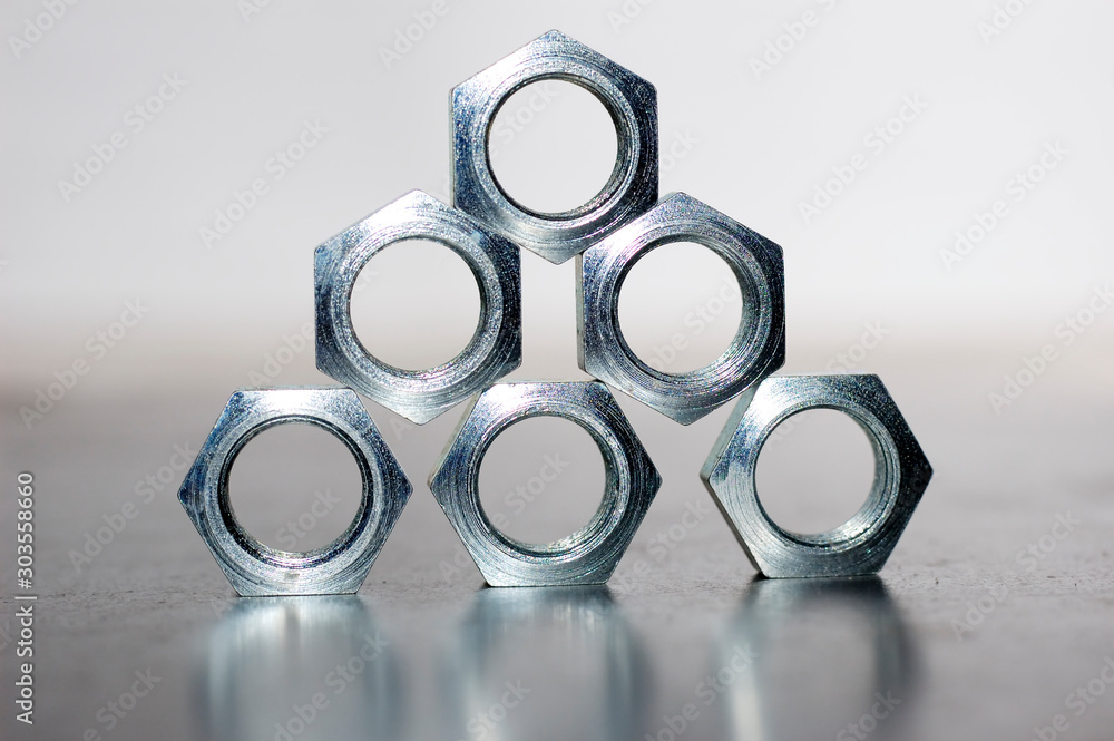Close-up of a pyramid of five chrome metal nuts Close-up of a pyramid of five chrome metal nuts