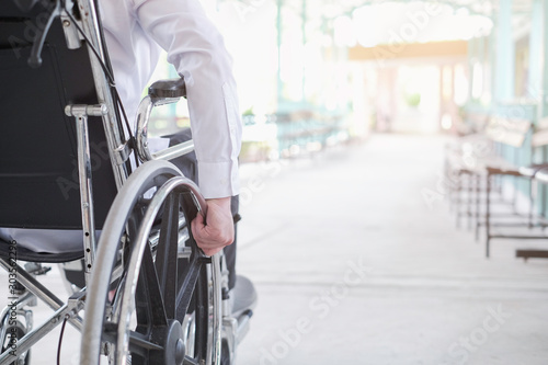 Cropped image of man holding wheelchair outdoors