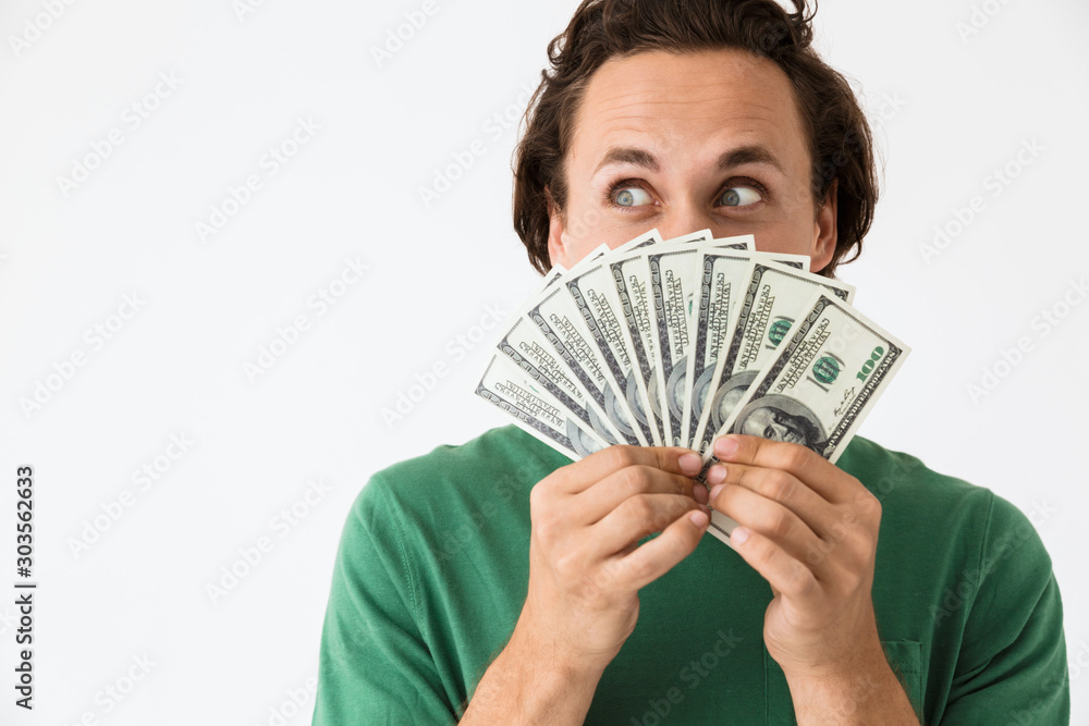 Image of optimistic brunette man covering his face with cash money Image of optimistic brunette man covering his face with cash money