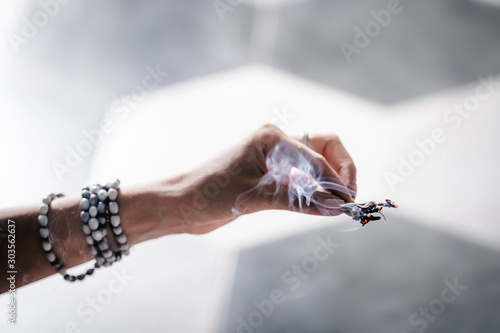 Woman's hands smudging burning sage, dry plant. Space, energy healing. Close up, copy space photo
