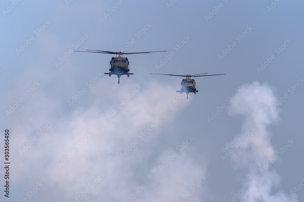 American Black Hawk helicopter Sikorsky UH - 60M attack takes off at the operation with weapons between smoke in battle war on the blue sky American Black Hawk helicopter Sikorsky UH - 60M attack takes off at the operation with weapons between smoke in battle war on the blue sky