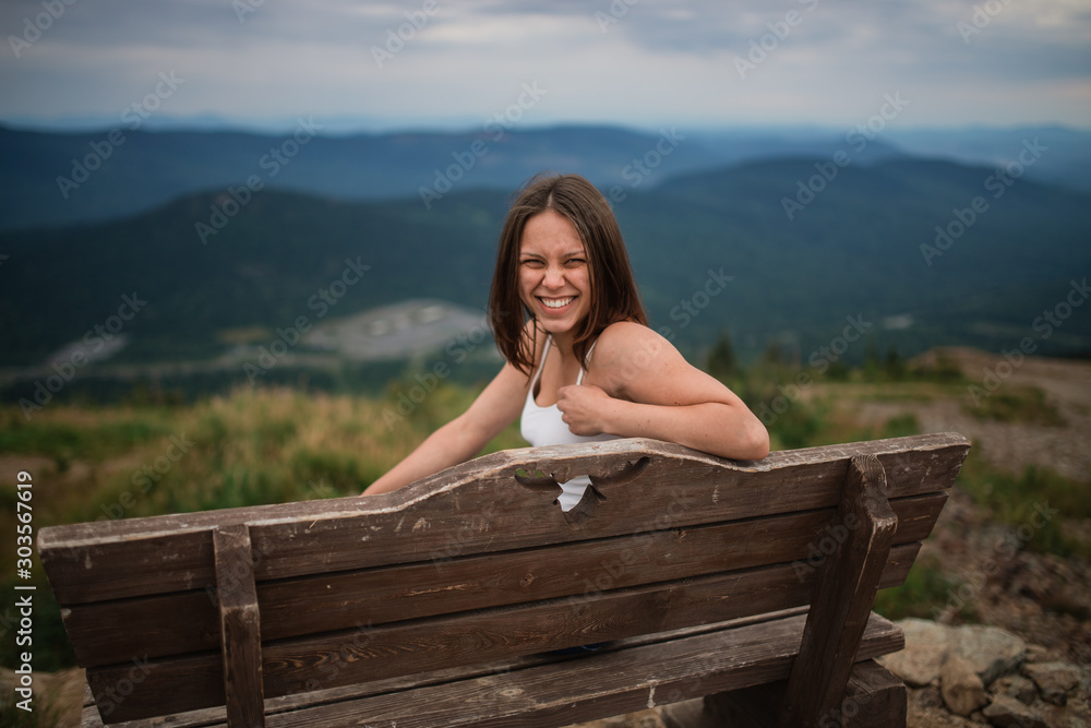 young girl sitting on a bench, beautiful view of the mountains. happy girl on the bench