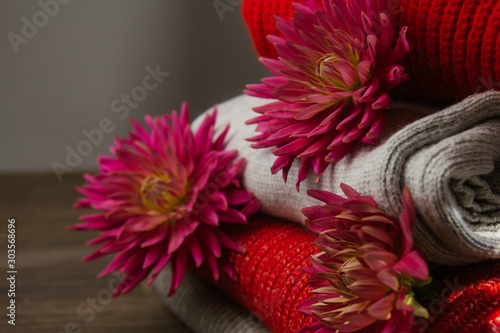 Pattern of colorful knitted sweaters closeup. Handmade merino wool product. A stack of folded clothes with flowers. © Yuliia