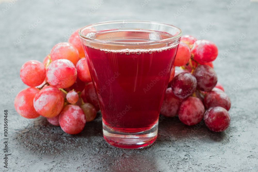 Glass of grape juice and a branch of grapes. Close-up.