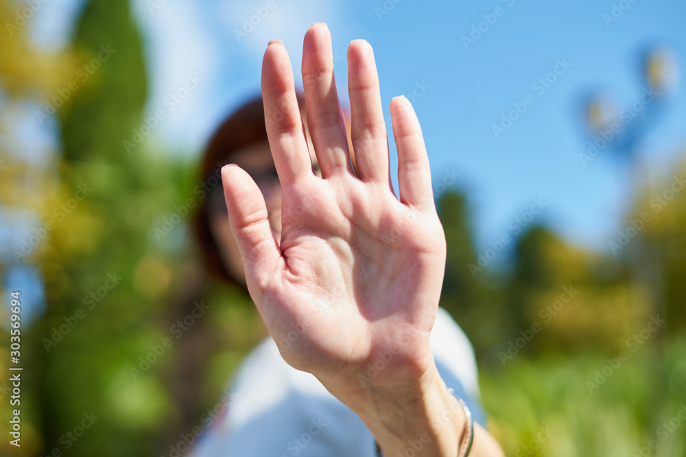 Unrecognizable woman shielding her face from camera. Concept of privacy, personal space, prohibition of photography. Female on blue sky, summer sunny day. Stop, taking pictures is forbidden Unrecognizable woman shielding her face from camera. Concept of privacy, personal space, prohibition of photography. Female on blue sky, summer sunny day. Stop, taking pictures is forbidden