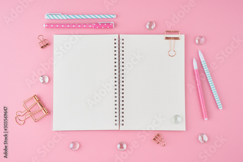 Blank notepad page in bullet journal on bright pink office desktop. Top view of modern bright table with notebook, stationery. Mock up, copy space, concept for diary