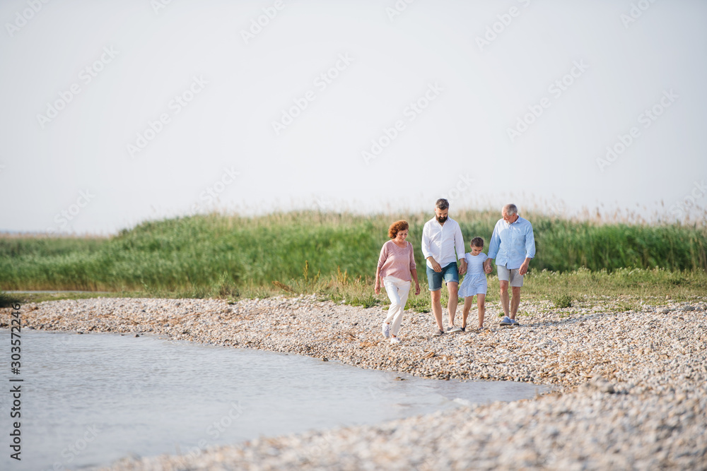 Multigeneration family on a holiday walking by the lake, holding hands.