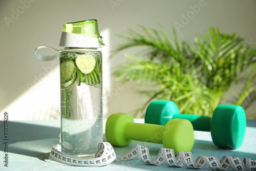 Tableau sur toile Bottle of healthy infused water, dumbbells and measuring tape on table