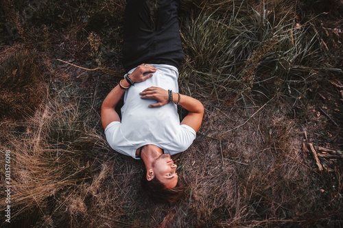 Foto Man lies on the grass in the middle of the forest relaxing - resting