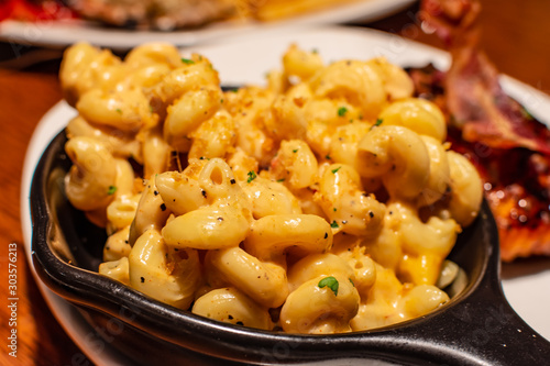 Macaroni and cheese also called mac and cheese or mac n cheese served in black small pan. Close up. photo