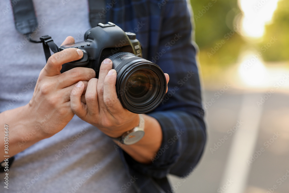 Handsome male photographer with camera outdoors, closeup