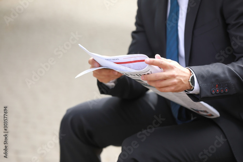 Handsome businessman with newspaper outdoors photo