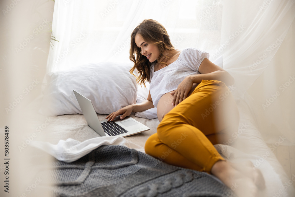 Happy young expectant mother is using gadget in room Happy young expectant mother is using gadget in room