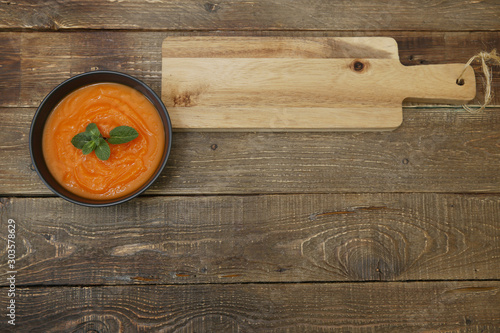 Pumpkin soup in a bowl isolated on a wooden rustic board with space for text or image. Menu, background, card. Flat lay. Top view. Healthy eating concept.