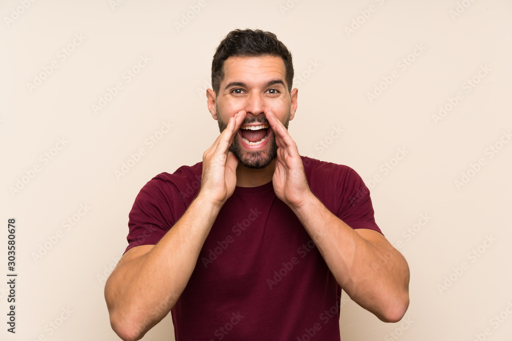 Handsome man over isolated background shouting with mouth wide open Handsome man over isolated background shouting with mouth wide open