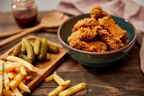 selective focus of delicious chicken nuggets, french fries and gherkins on wooden table