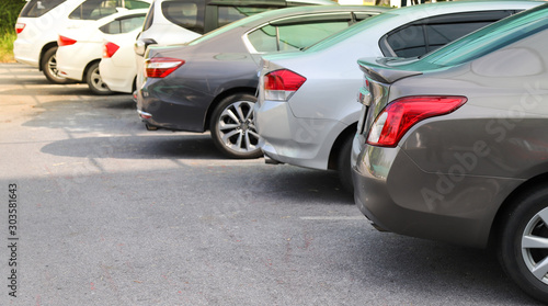 Closeup of rear, back side of brown car with other cars parking in outdoor parking area in bright sunny day. 