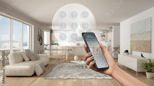 Smart home technology interface on phone app, augmented reality, internet of things, interior design of modern kitchen with connected objects, woman hand holding remote control device photo