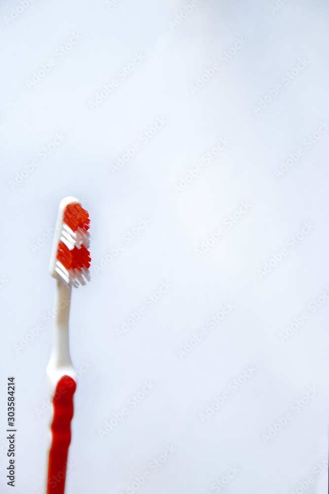 Red toothbrush on a white background. A toothbrush with striped lint and a red handle. A symbol of cleanliness and dental health. Dental supplies and household items. Oral hygiene.