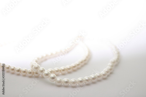 Beads of pearls on a white background. Pearls illuminated by bright light. Decoration for the holiday of round white elements.
