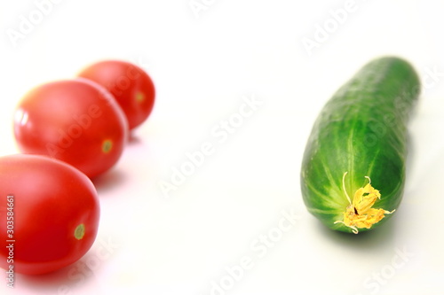 Red tomatoes and green cucumber on a white background. Fresh vegetarian harvest from the farm.