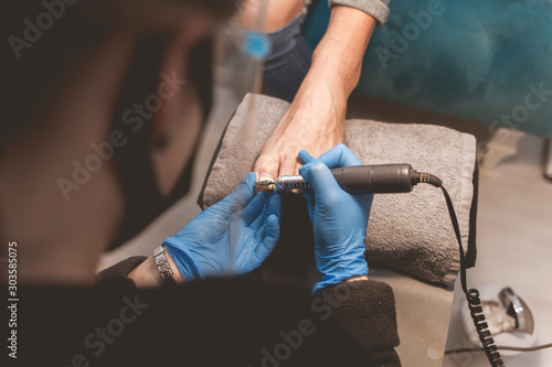 Pedicure master uses nail file drill for preparing nails for pedicure