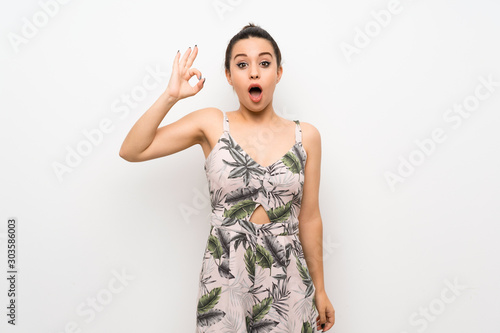 Young woman over isolated white background surprised and showing ok sign © luismolinero