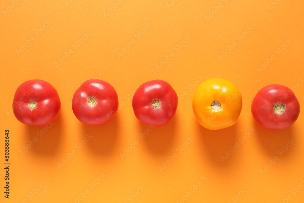 Wall Mural Yellow tomato among red ones on color background