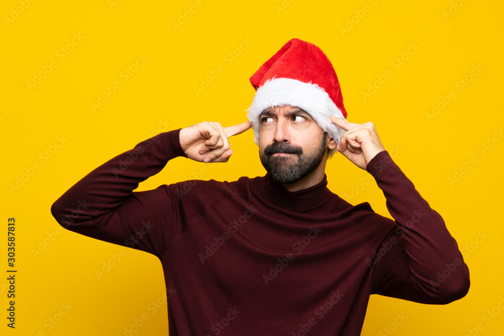 Fototapeta premium Man with christmas hat over isolated yellow background having doubts and thinking