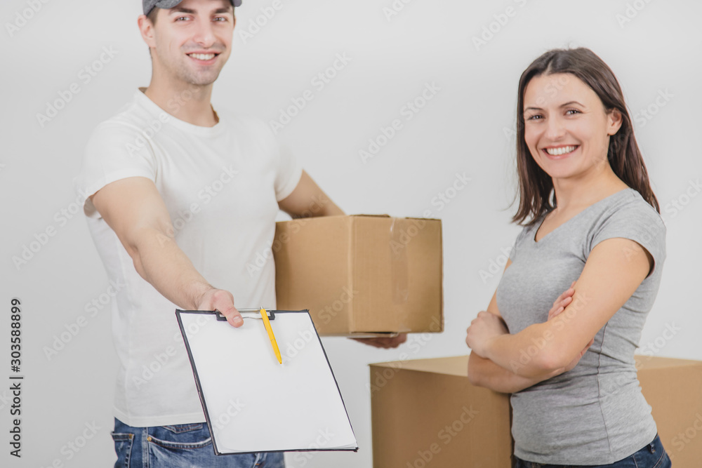 Cropped blurred happy delivery man transported boxes into new apartment of lovely young woman and is showing signed declaration, smiling. Both are happy for cooperation. Cropped blurred happy delivery man transported boxes into new apartment of lovely young woman and is showing signed declaration, smiling. Both are happy for cooperation.