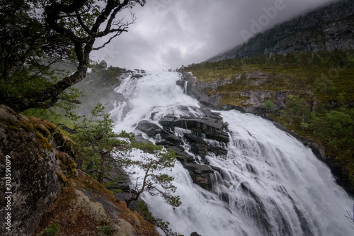 Nyastolsfossen waterfall raging down in dark weather circumstances Norway