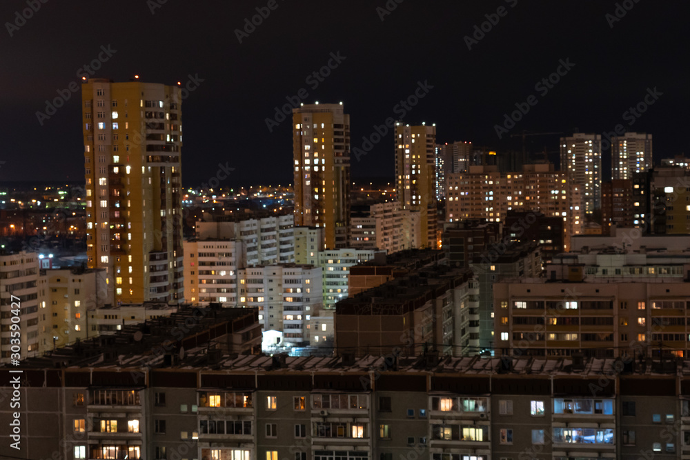 Residential areas on a winter night. Glowing windows of multi-storey residential buildings. A lot of parked cars in the yards