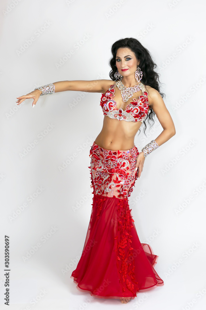 Brunette beautiful long red dress to perform belly dance on a white background Brunette beautiful long red dress to perform belly dance on a white background