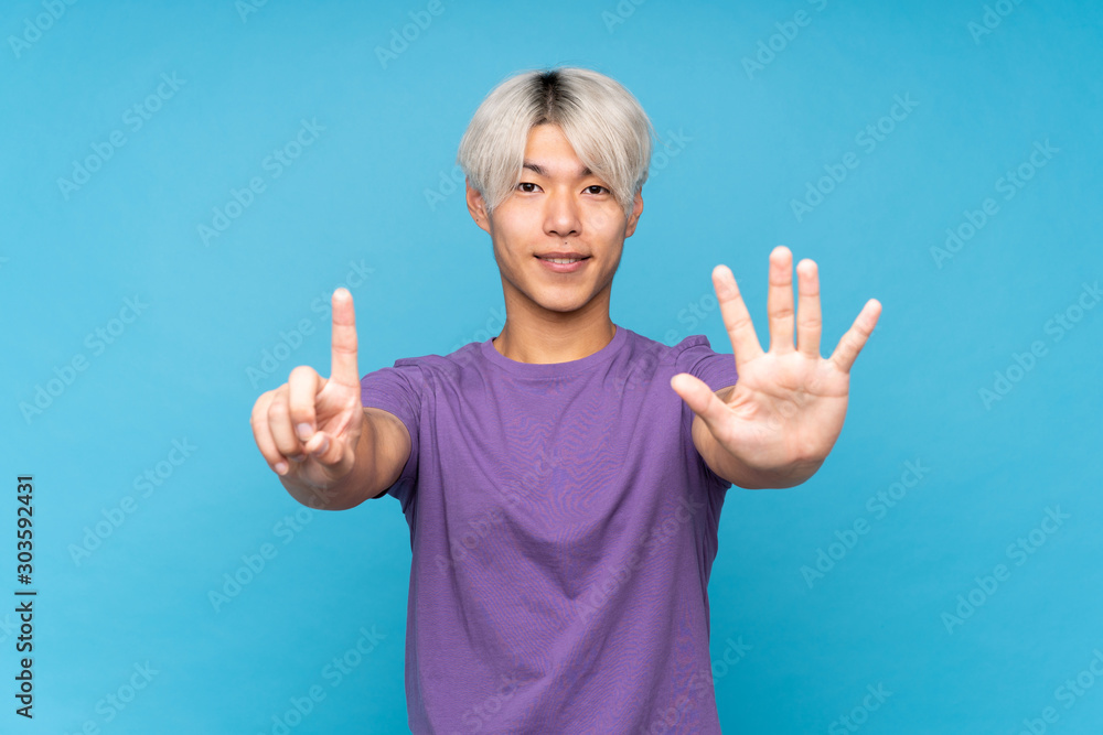 Young asian man over isolated blue background counting six with fingers Young asian man over isolated blue background counting six with fingers