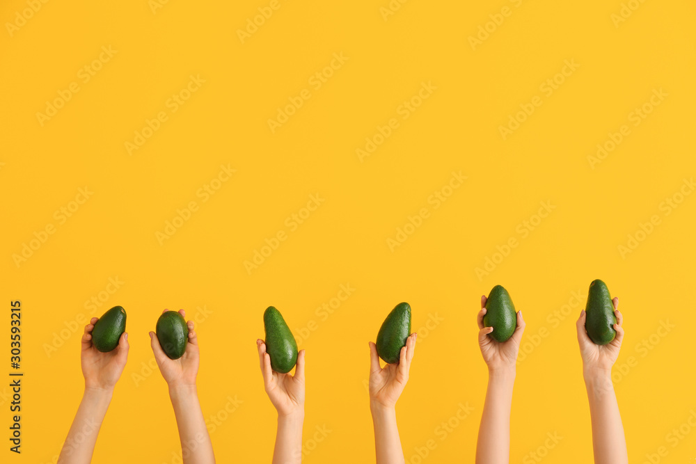 Female hands with fresh avocados on color background Female hands with fresh avocados on color background