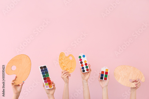 Female hands with painter's supplies on color background