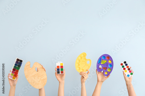 Female hands with painter's supplies on light background