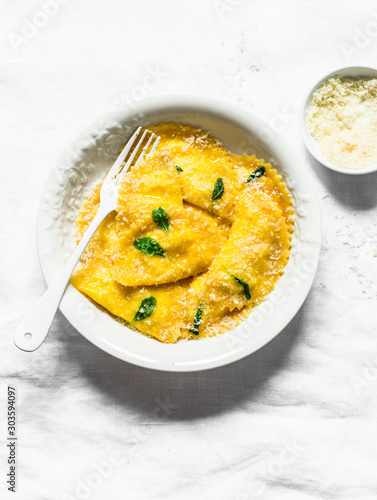 Pumpkin dough cheese ravioli with sage butter on a light background, top view. Comfort autumn winter food in mediterranean style