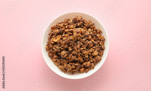 Bowl with tasty granola on color background