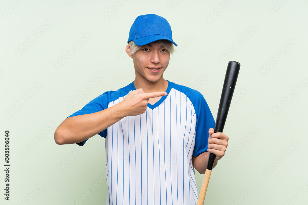 Young asian man playing baseball over isolated green background and pointing it Young asian man playing baseball over isolated green background and pointing it