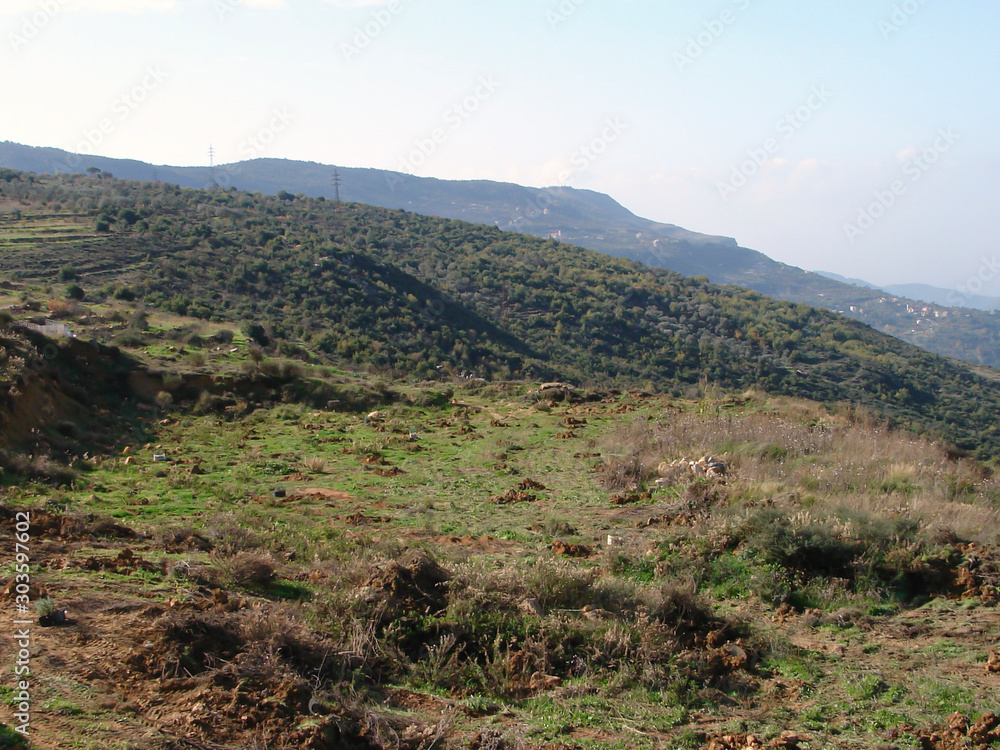 Beautiful landscape in the mountains of the cross Deir El Kamar. View of foggy hills covered by forest.