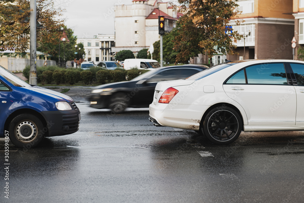 Two cars on the pedestrian crossing in the city. Traffic violation concept photo. White car on rainy day. Keep the distance. Before the crash. Intruder on the road.