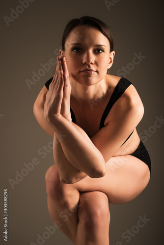 Yoga lover doing Garudasana on a dark background