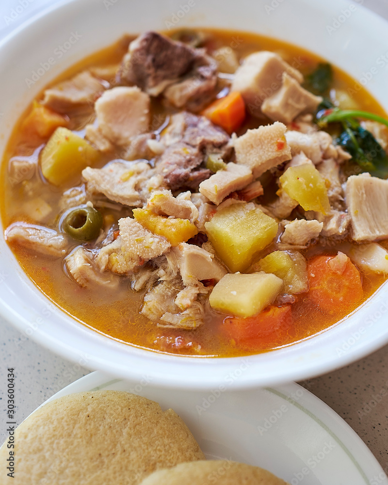 Mondongo soup, made with cow stomach, traditional dish of the Caribbean countries and Venezuela, served in a deep white bowl, accompanied with arepas and avocados Mondongo soup, made with cow stomach, traditional dish of the Caribbean countries and Venezuela, served in a deep white bowl, accompanied with arepas and avocados