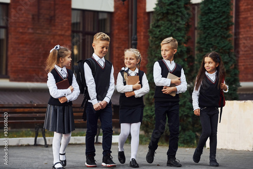 Obraz na płótnie Group of kids in school uniform that is outdoors together near education buildin