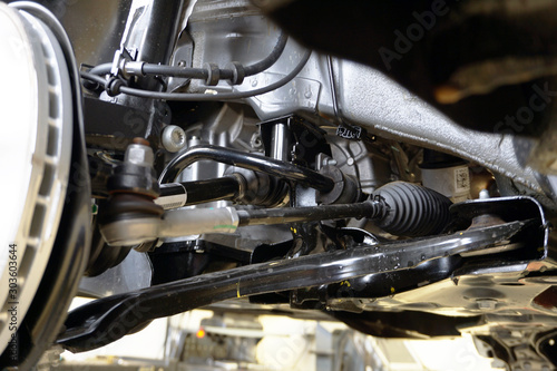 Elements and structure of the front suspension of a modern car. Close-up of the front suspension arm, steering rod and tip, drive shaft, protective anthers, stabilizer. Repair and maintenance.